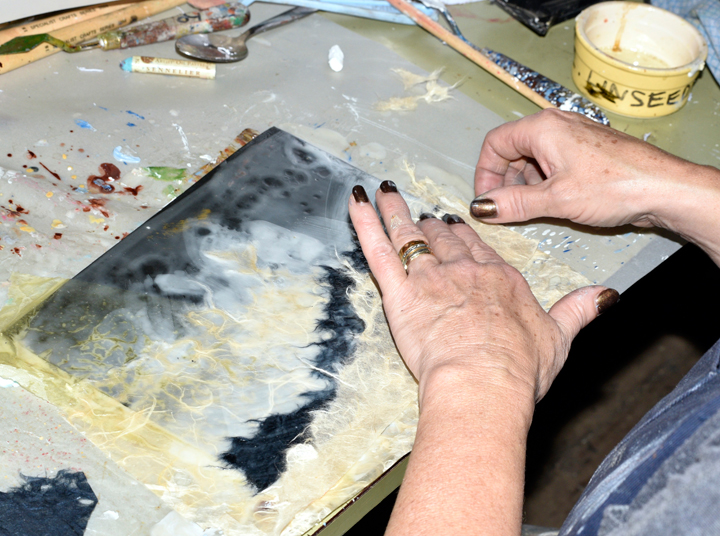 Jo applying collage to an encaustic